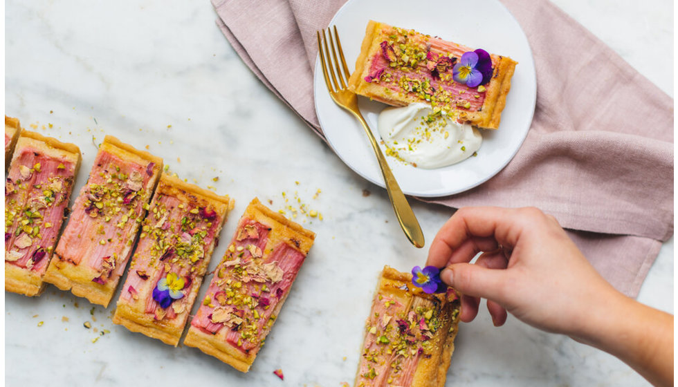 Slices of rhubarb tart decorated with edible flowers. Cooked by Doggart and Squash.