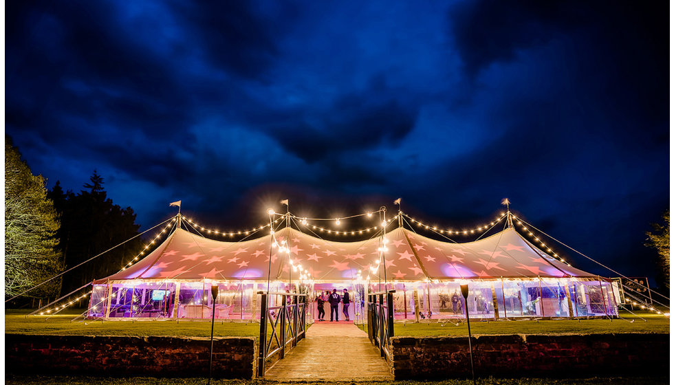 A marquee beautifully lit up at night with festoon lights.
