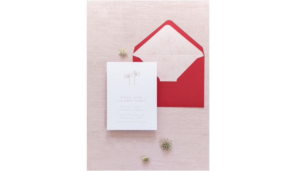 A beautiful flat lay of a pink invitation with a beautiful maroon envelope.