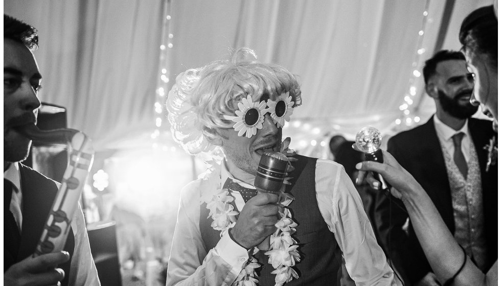 One wedding guest wearing a wig and fun glasses on the dance floor. 
