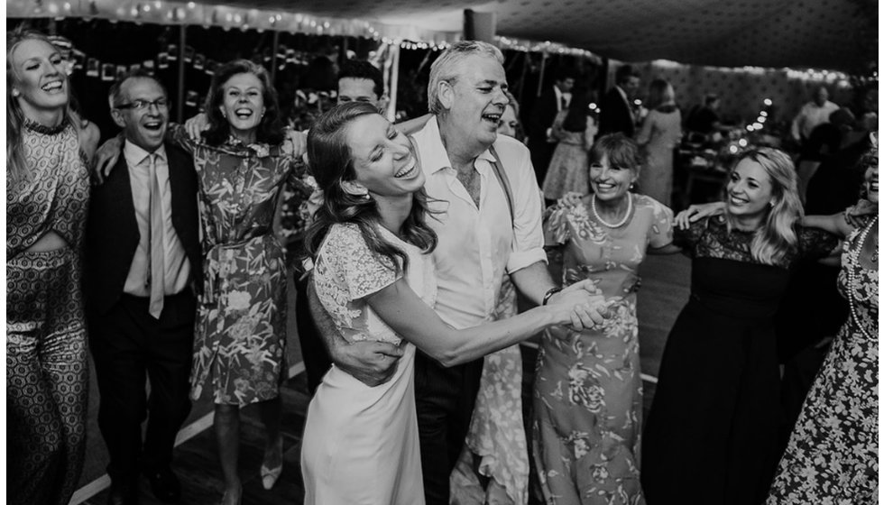 The bride and her father dancing on the dancefloor surrounded by guests.