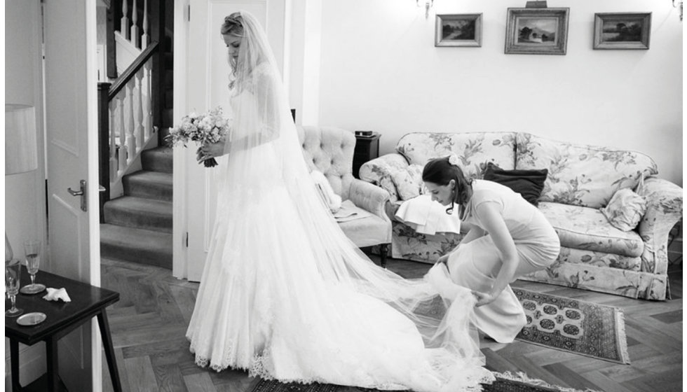 The bride's made of honour helping her with her dress.