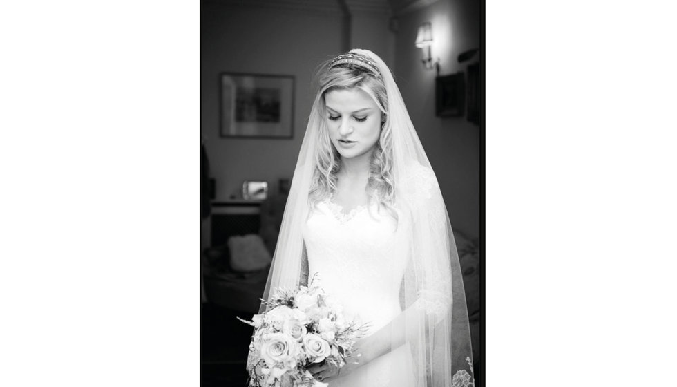 A black and white portrait of the bride with her bouquet of roses.