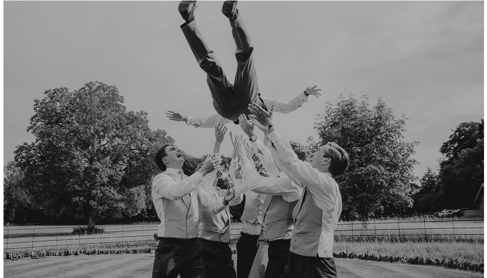 The ushers throw the groom high into the air for the photographer to capture.