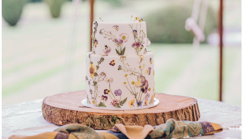 The wedding cake with pressed edible flowers decorated on it.