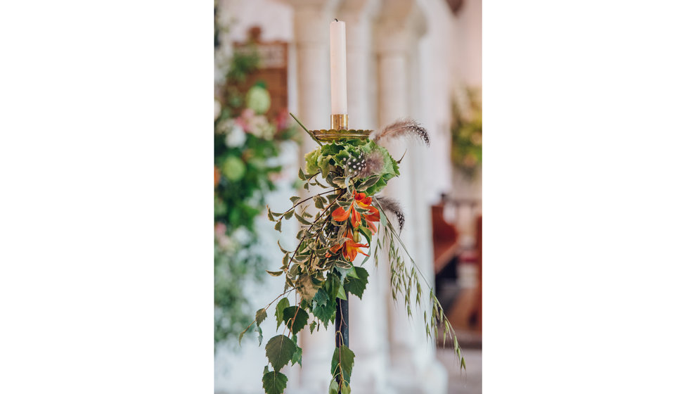 A close up of the Church flowers that are decorated with feathers.