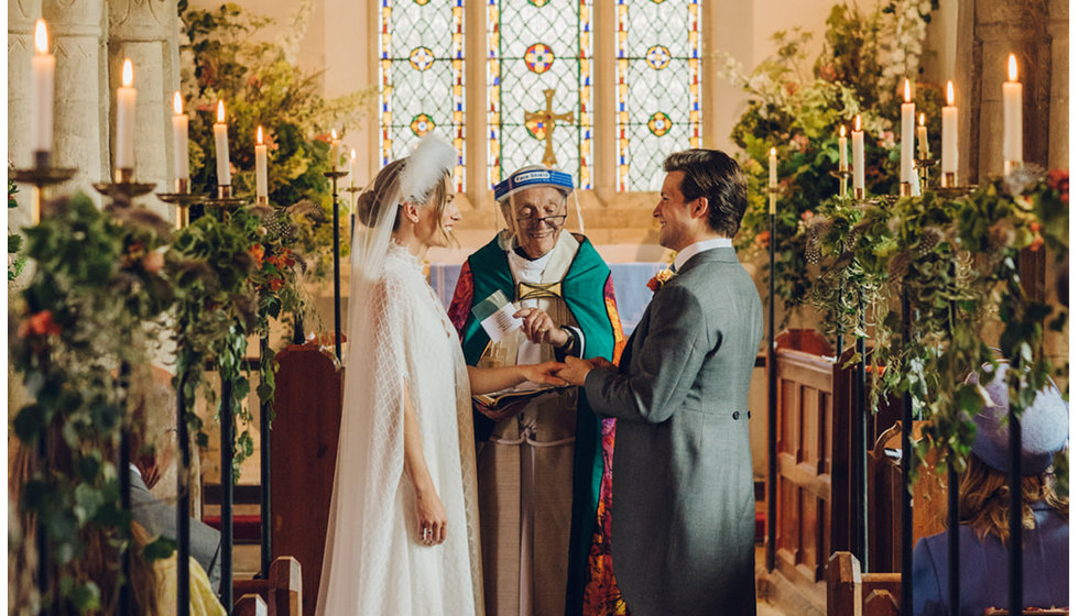 The bride and groom in the Church with the Vicar wearing a COVID secure visor.