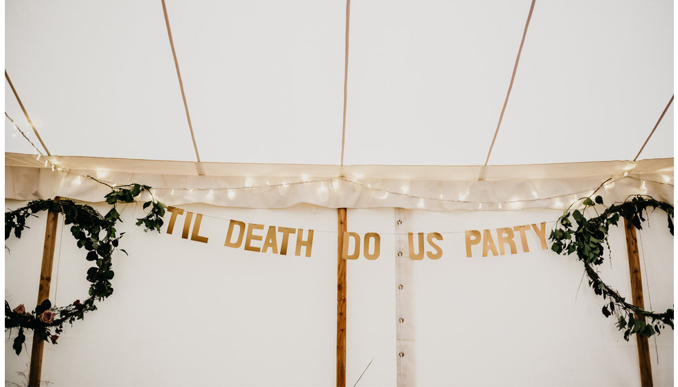 A cardboard sign saying 'Til Death do us Party' - hanging in the marquee.
