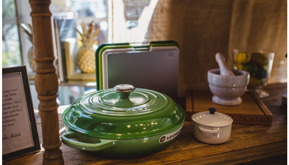 A rosemary coloured Le Creuset casserole dish, some green chopping boards and a petite le Creuset pot.