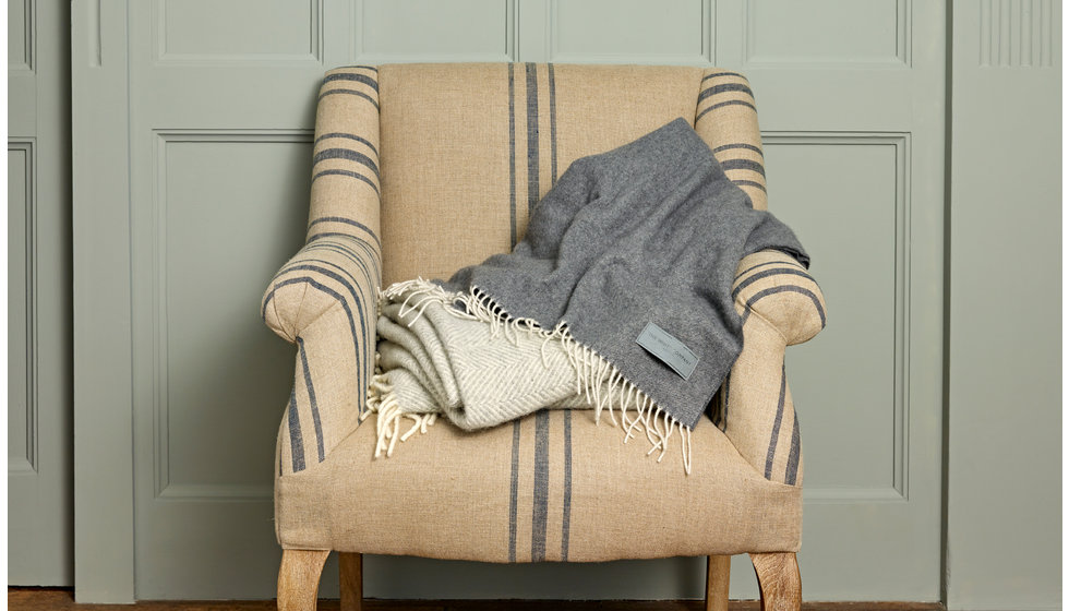 A stripe OKA armchair with a cashmere blanket on it.