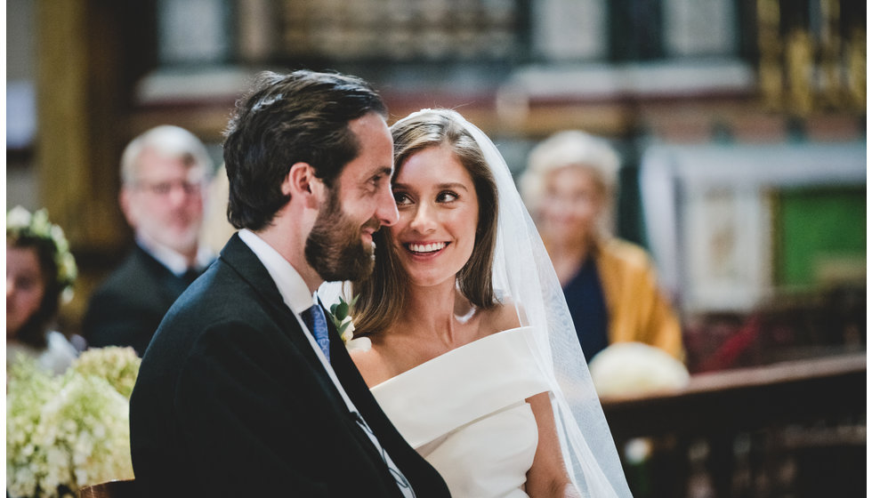 The bride and groom smiling at each other during their ceremony at The Brompton Oratory.