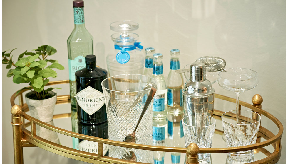 A cocktail trolley with sprits and drinks accessories.