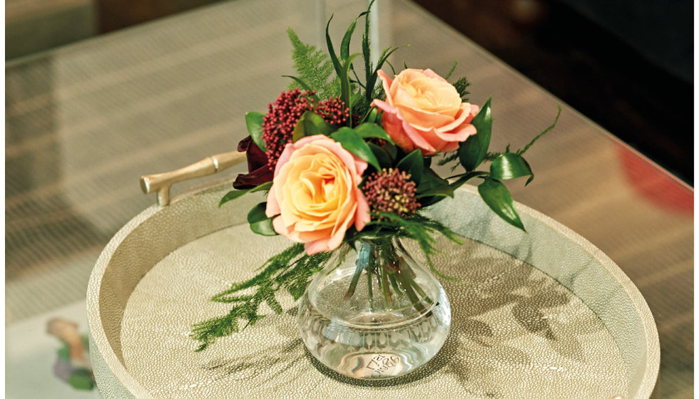 A small bud vase of peach and burgundy roses from The Vintage List on a faux shagreen grey tray. 