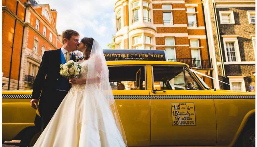 The bride and groom kissing next to a yellow NYC yellow taxi at their London wedding.
