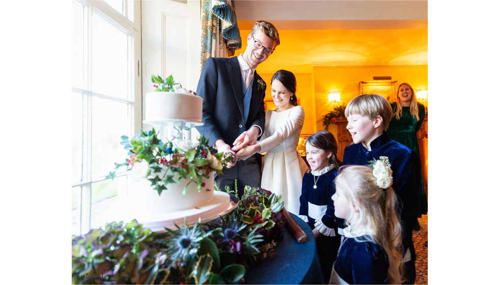 The bride and groom cutting the cake with their flower girls and page boys.