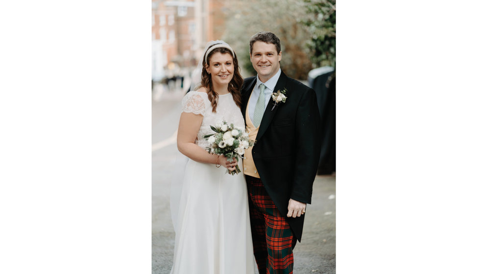 Sarah and Fergus after their wedding reception. The bride wears a short sleeve wedding dress by Laure de Sagazan and Fergus wears a morning suit with his family tartan trousers.