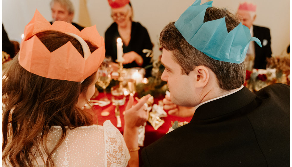 The bride and groom both wearing hats from their christmas crackers.