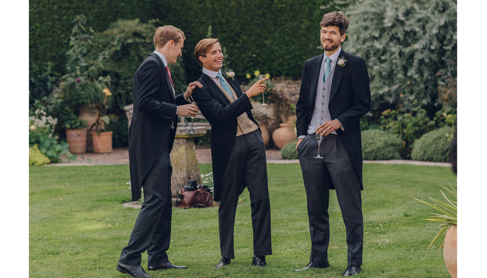 Three male guests in morning suits at a summer wedding. 