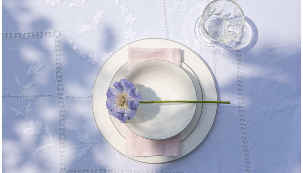 A dinner table, side plate and bowl from Alice Peto's rainbow collection on a white embroidered tablecloth. 