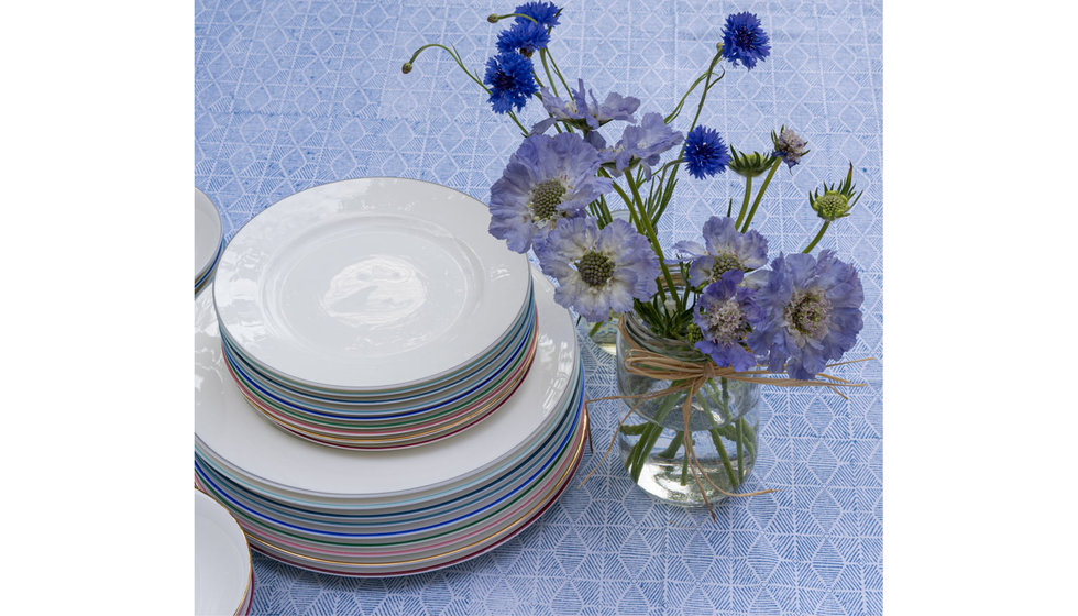 A stack of Alice Peto's rainbow plates on a blue tablecloth.