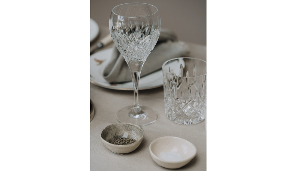 Royal Scot Crystal Wine Glasses on a chalk coloured linen tablecloth next to ceramic salt and pepper pinch pots. 