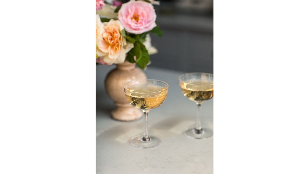 Champagne Coupes from The Vintage List in front of a ceramic vase of english roses.