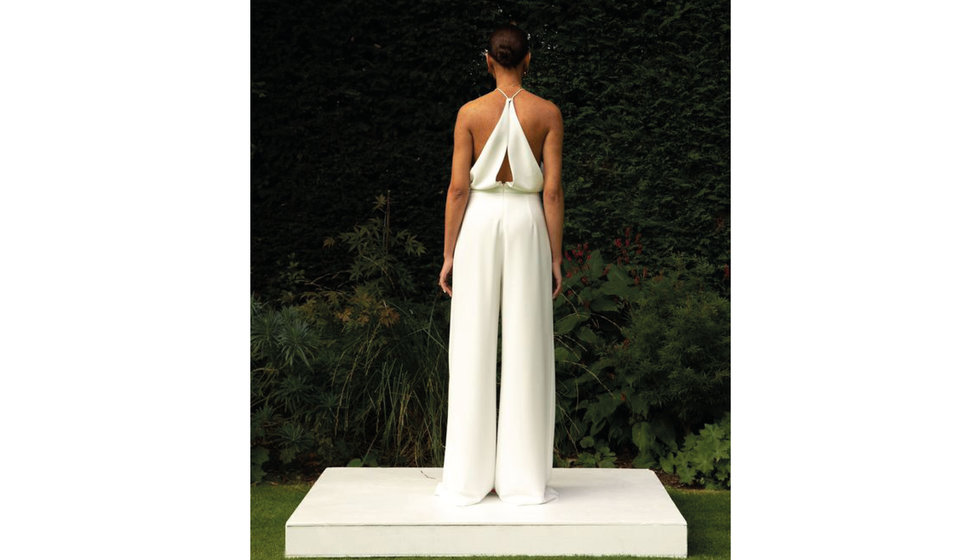 A model showing the back of a wide leg trouser jumpsuit with a cross back. 