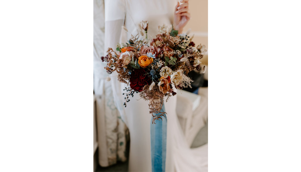 Sophie holds her bouquet of winter flowers wrapped with a blue ribbon.