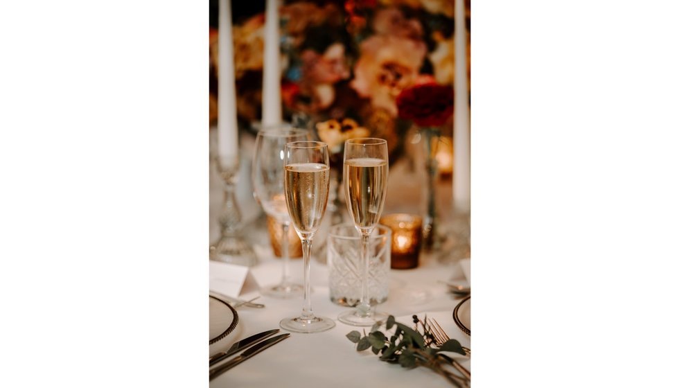 A close up of two champagne flutes of champagne on the table. 