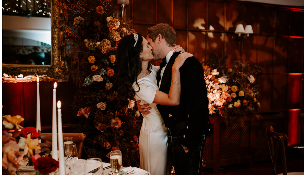 Sophie and Graeme inside their wedding venue at Langrish House where their florist transformed the room into a magical winter garden with a large floral installation of seasonal roses.