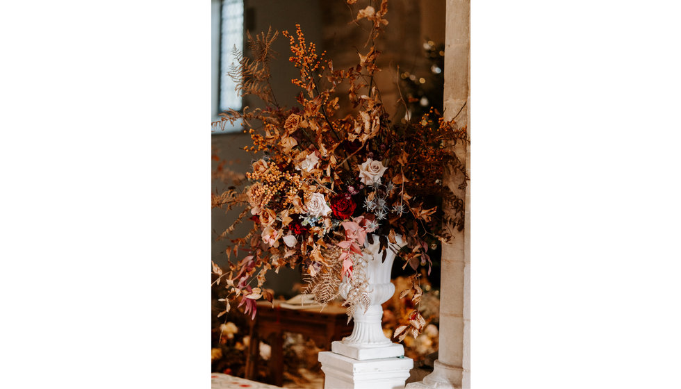 A large white urn filled with wintery florals and foliage.