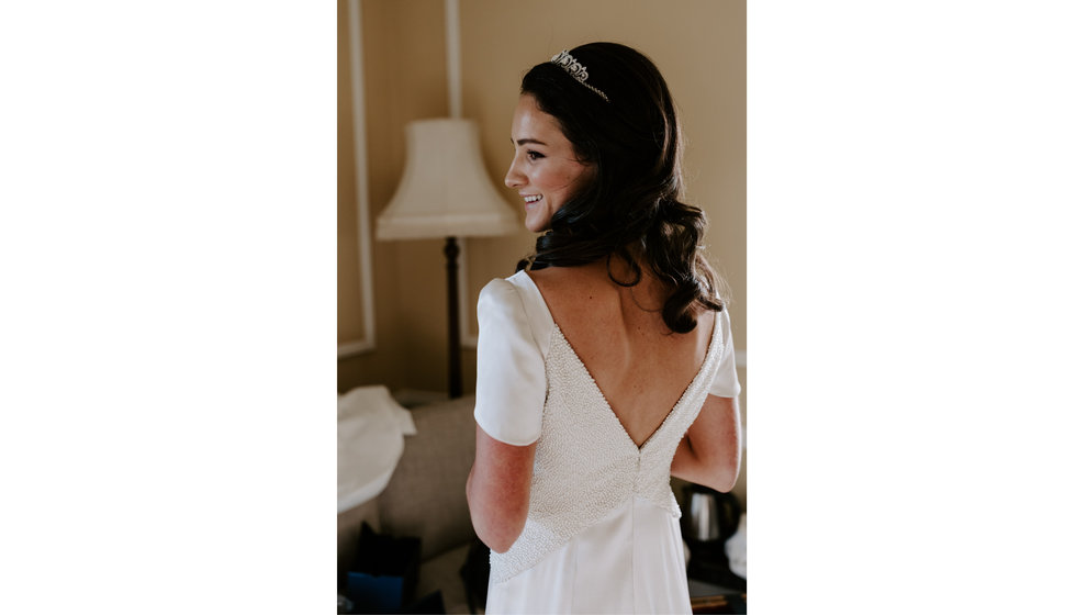 Sophie's bespoke wedding dress has a v shape low back to her wedding dress. She wore diamond hair accessories with her hair loosely curled.