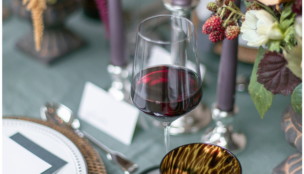 A close up of red wine glasses filled with red wine at a formal table.