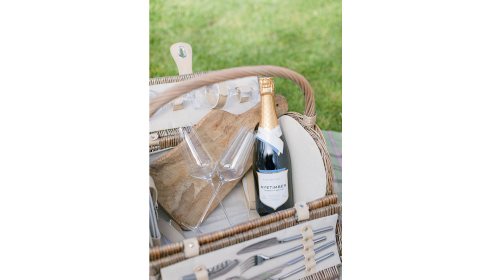 A picnic hamper with a bottle of Nyetimber. 