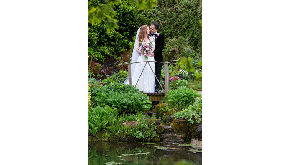 Sarah and Nico stand by a pond at their East Sussex wedding.