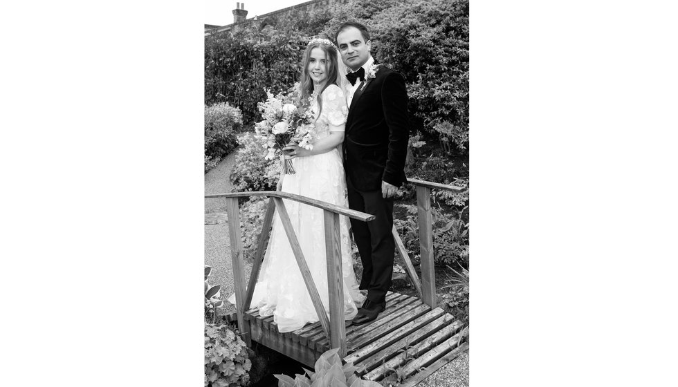 Sarah and Nico stand on a bridge in the garden at their East Sussex Wedding.