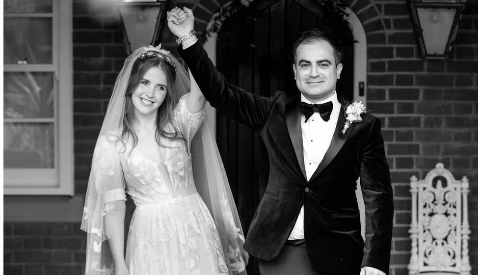 Sarah and Nico hold hands in the air after being married. 