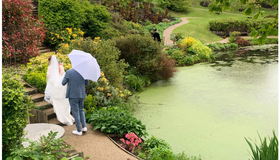 Sarah and Nico walk by a pond at their East Sussex wedding.