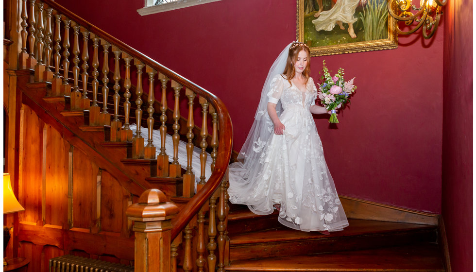 Sarah walking down the stairs in her wedding dress.
