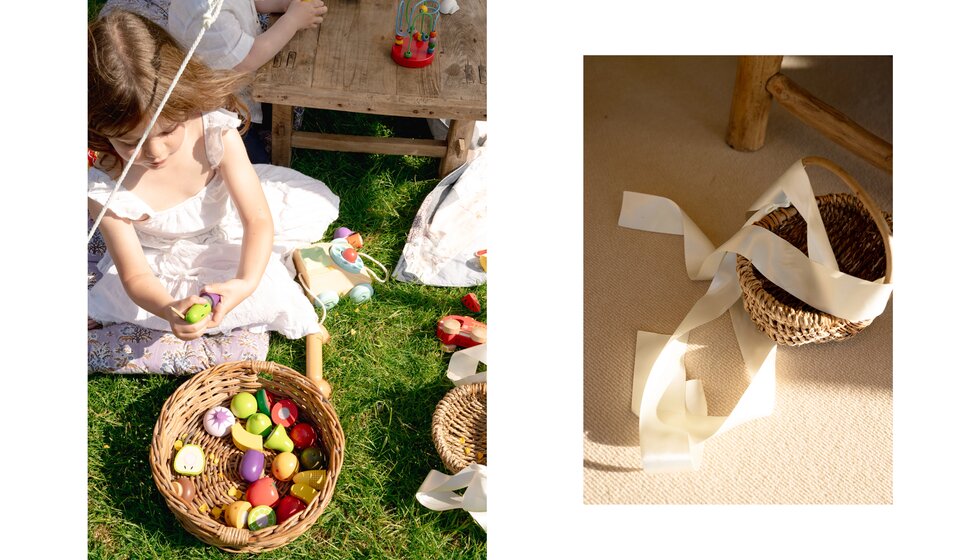 Charlotte & Harry's Magical Meadow Marquee Wedding in Oxfordshire: A Flower Girl dressed in embroidery anglaise address playing with a toy next to a flower basket