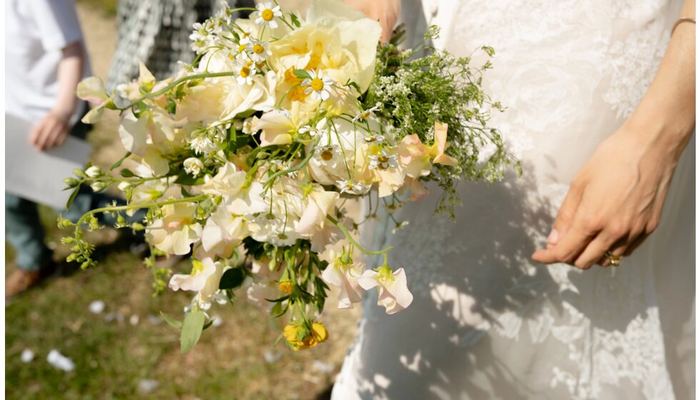 Charlotte & Harry's Magical Meadow Marquee Wedding in Oxfordshire: A bridal bouquet featuring delicate yellow and white flowers, and green foliage
