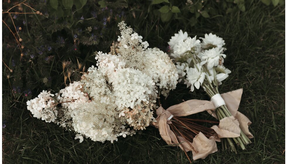 Whimsical Floral Wedding in London Park | Seasonal white bridal bouquet with hydrangeas and white bridesmaids' wedding bouquet placed on a grass