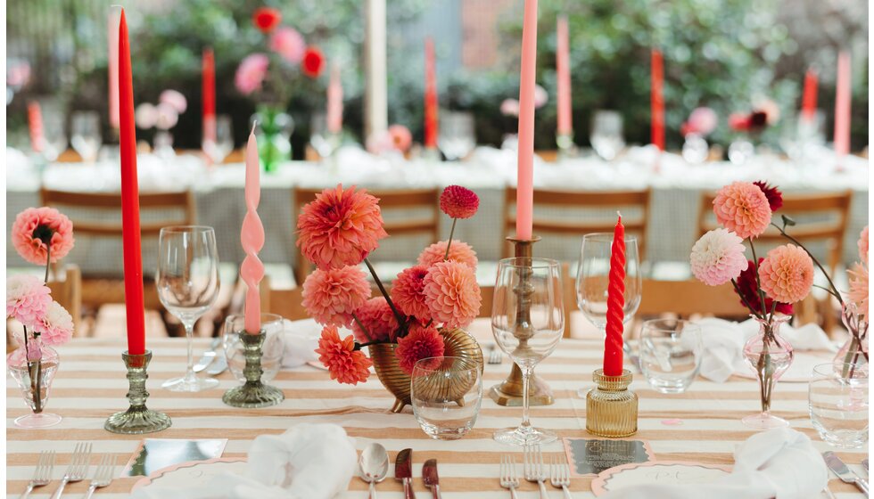 Whimsical Floral Wedding in London Park | Floral-inspired wedding tablescape with neutral striped tablecloth, pink and red flowers in colourful vintage vases, and a mix of tableware