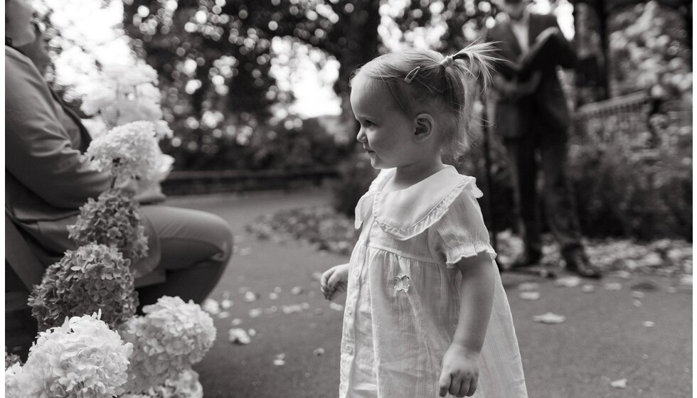 Whimsical Floral Wedding in London Park | A black and white photo of a flower girl wearing white linen flower girl dress