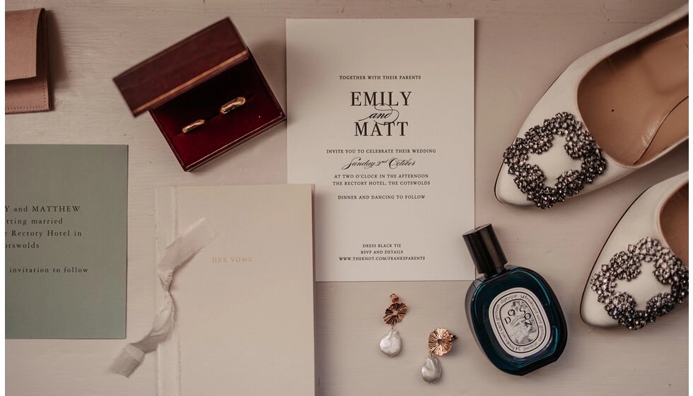 The Ultimate Wedding Planning Checklist | A flatlay photo showing elegant wedding stationery, next to wedding shoes and jewellery, including wedding bands.