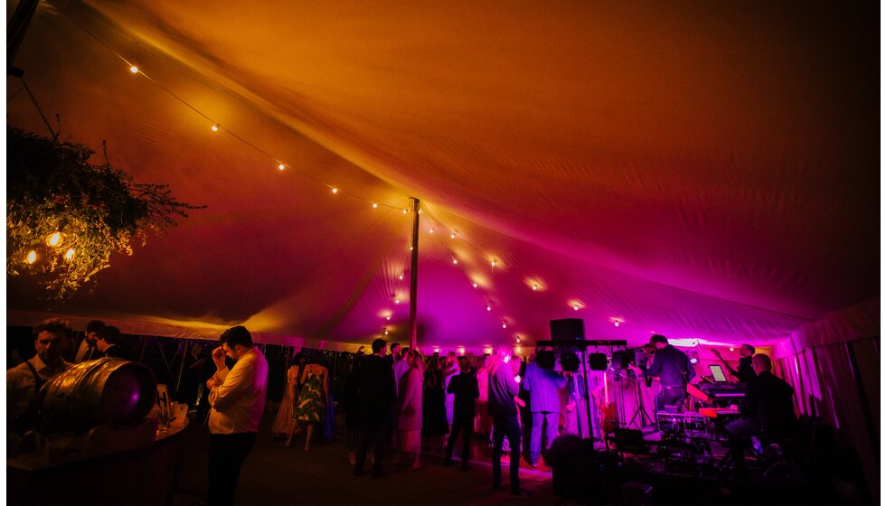 The Wedding Present Company | A wedding party inside a traditional English tent with festoon lights