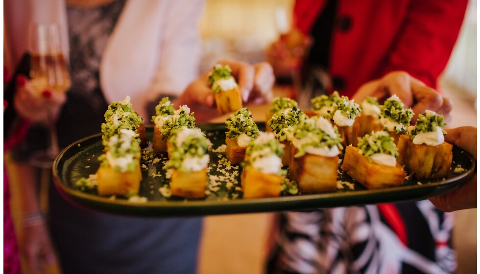 The Wedding Present Company | A wedding catering staff from Doggart & Squash serves rolls of canapes to the wedding guests.