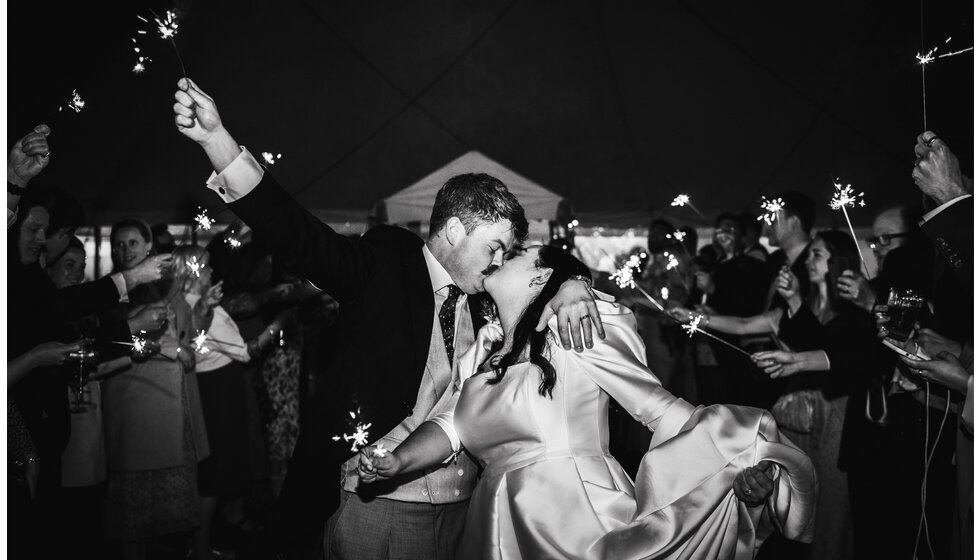 The Wedding Present Company | A groom and bride kiss during the send-off with sparkles