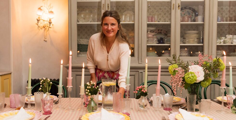 Supper Club with Skye McAlpine | Skye McAlpine setting table in front of light green vintage display cabinet with crockery