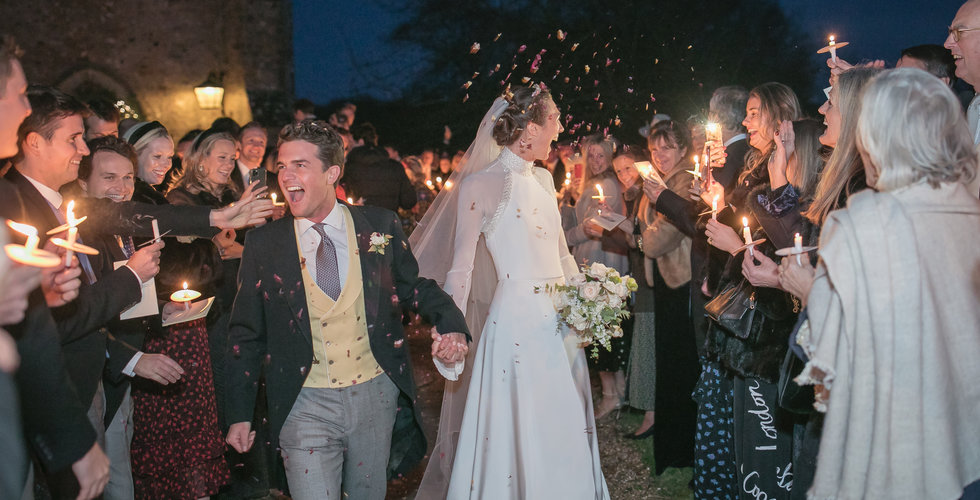 Image of Tania and Will leaving the Church with all their guests holding a candle and throwing confetti. 